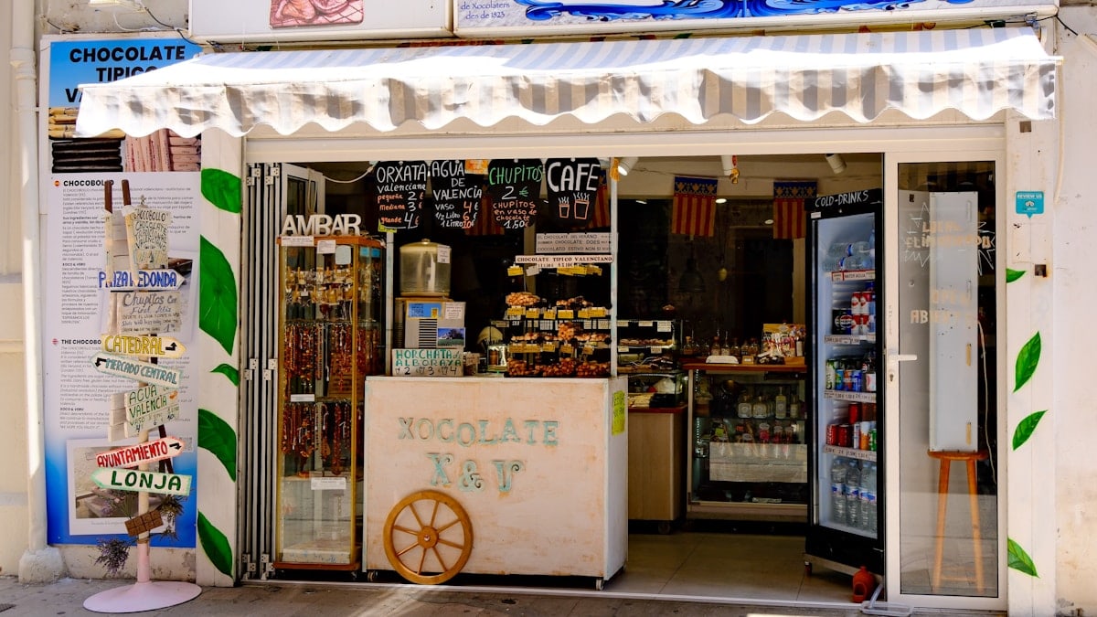 The colorful storefront of a traditional Valencian chocolate shop, Xocolates Xoco & Vero, with hand-painted signs and local specialties on display.